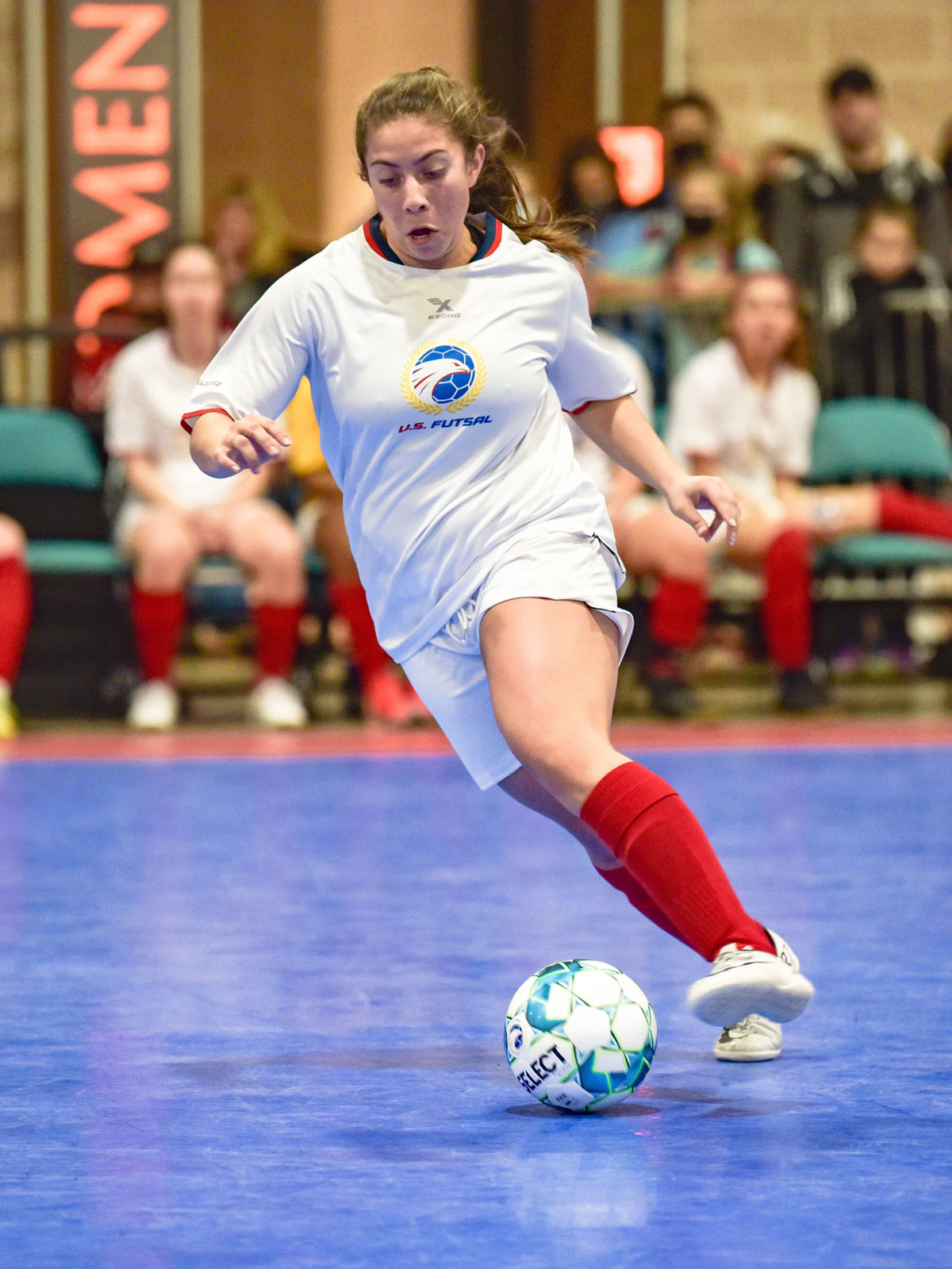 Woman running with futsal ball on court